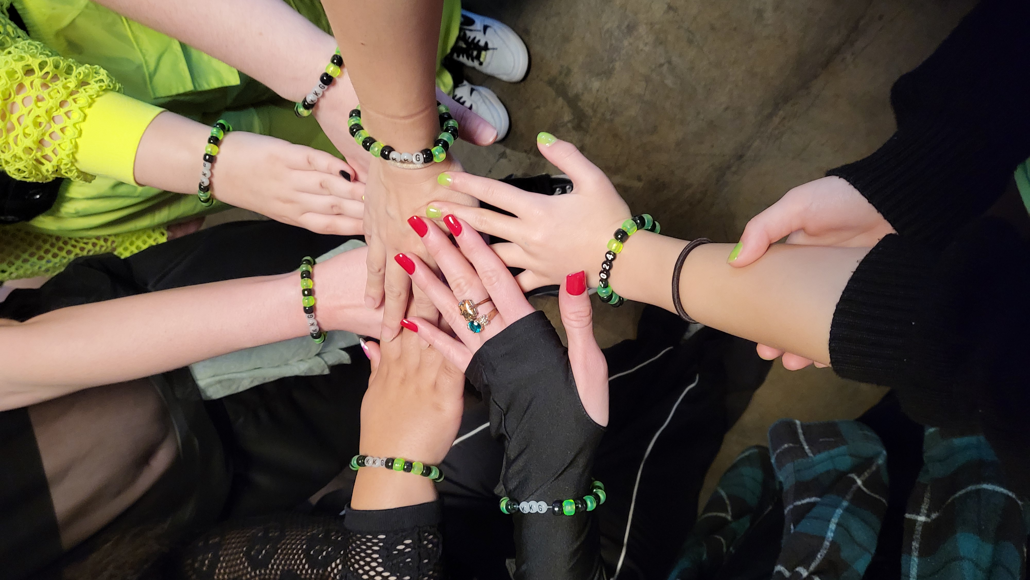 KKG team bracelets — hands stacked in formation